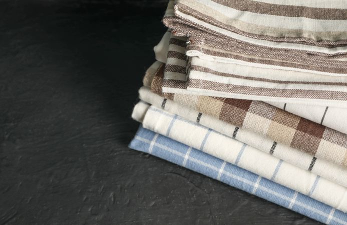 Stack of fabric napkins on dark table, space for text