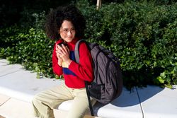 Woman with curly hair sitting outside holding coffee cup