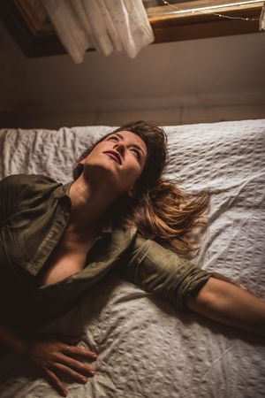 Tired woman lying on bed and looking up