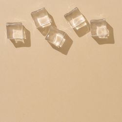 Flat lay of ice cubes on beige background with shadows