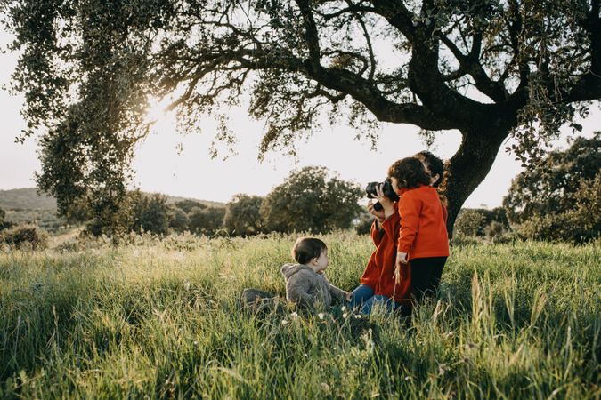 Young child looking through her mother’s camera in a park