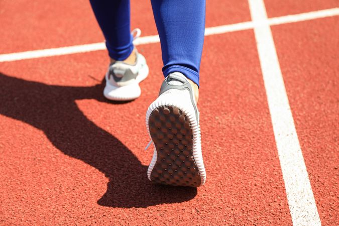 Girl walking on red athletic track, close up