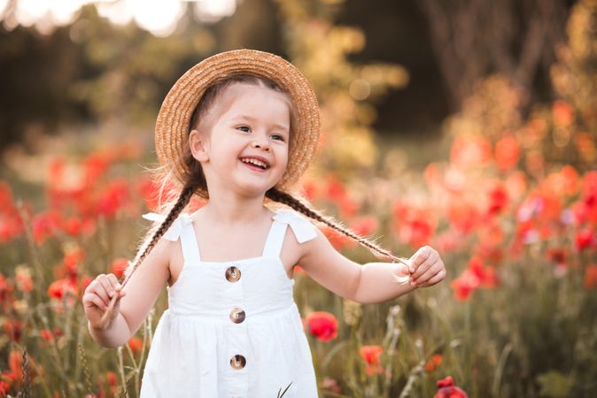 Happy smiling child girl 4-5 year old with red poppy flower in meadow outdoor