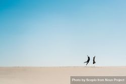 Man and woman jumping on sand  under blue sky 43V6x5