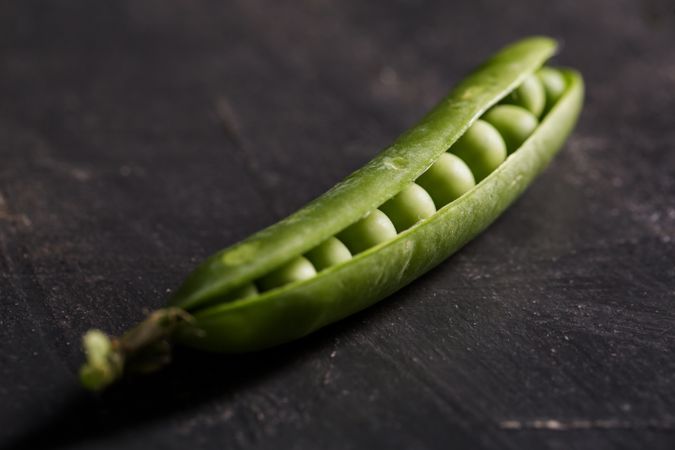 Fresh peas and pea pods on dark background