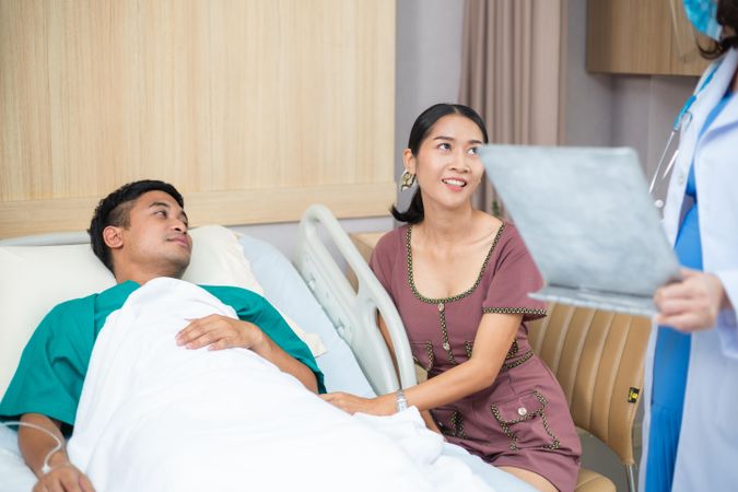 Woman supporting her husband in hospital while doctor visits