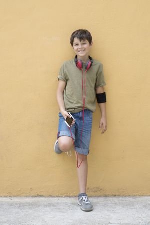 Smiling teen wearing a green T-shirt listening to music