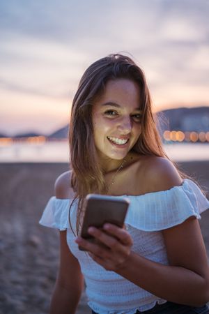 Cheerful young woman using smartphone on resort