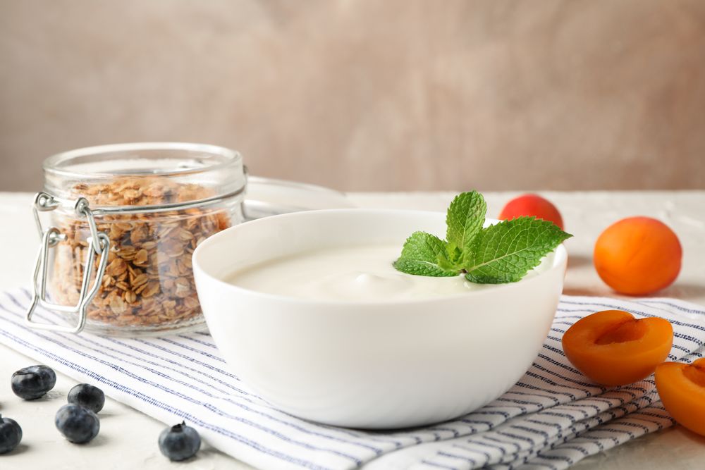 Composition with granola, yogurt and fresh fruits on cement background