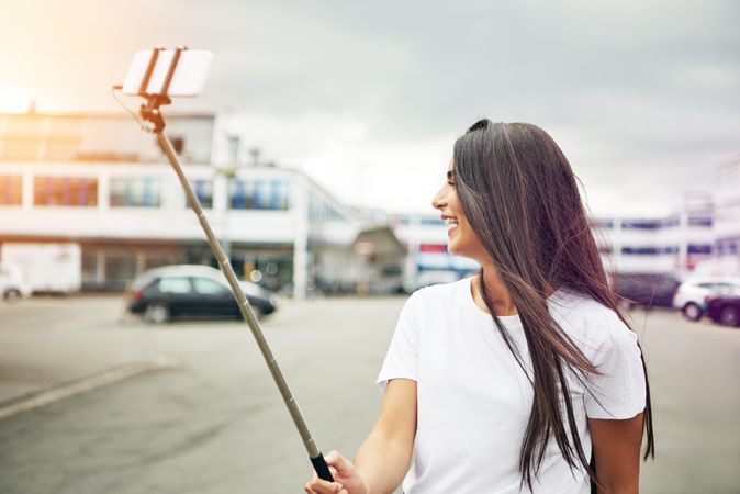 Woman looking away from selfie stick as she takes photo of herself
