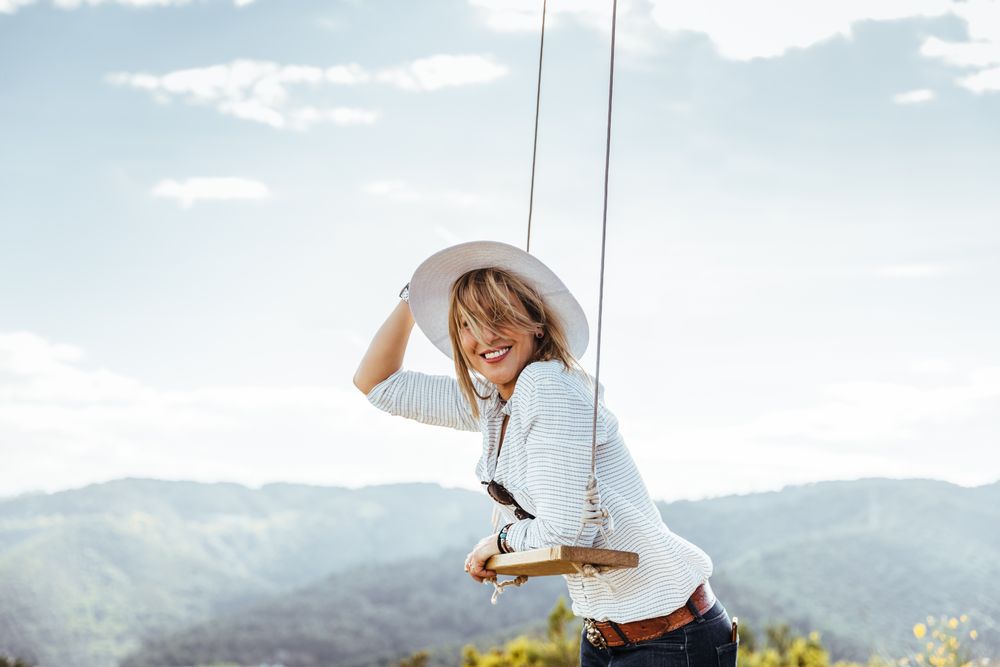 Happy woman with hat next to a swing