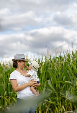 Adorable mother and child on hand enjoying and laughing in field