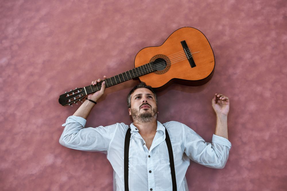 Man resting in water with guitar at seaside