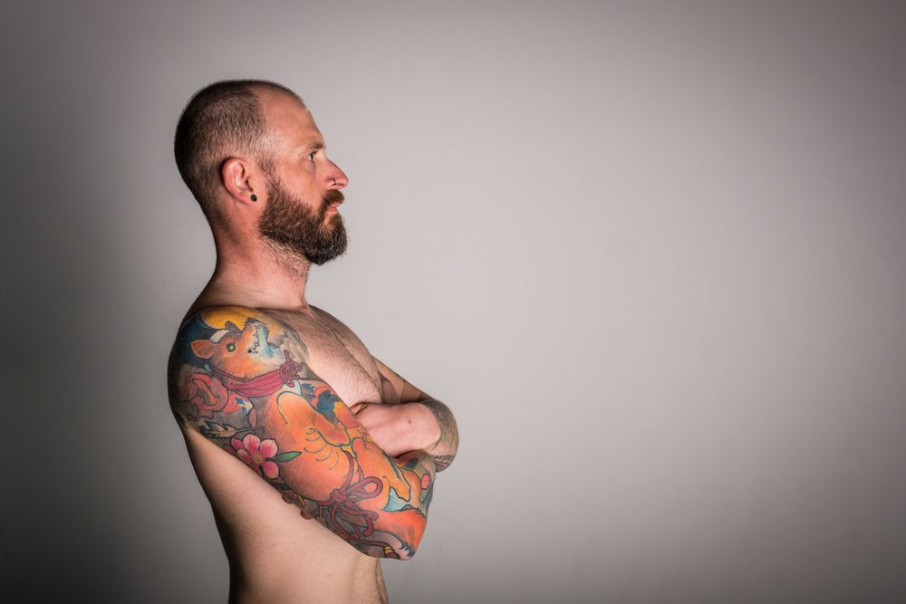 Young bearded guy with tattoos on hand