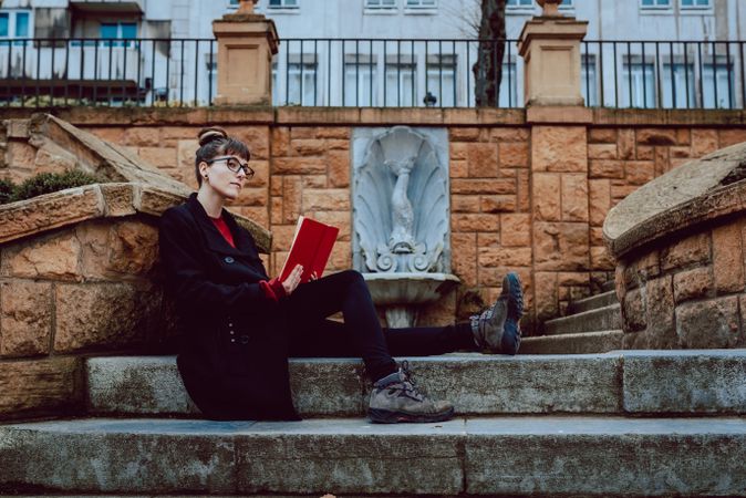 Young woman reading book on steps