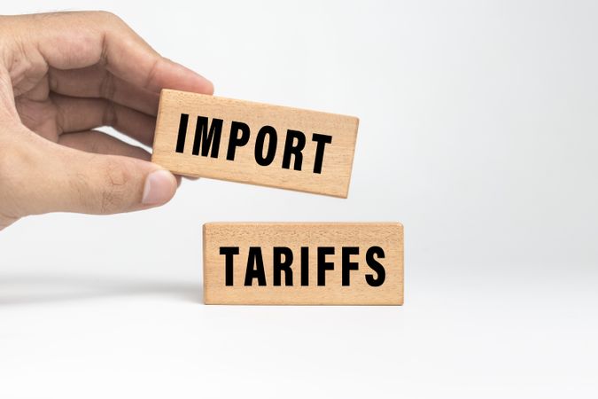 male hand put import tariffs word text on wooden blocks