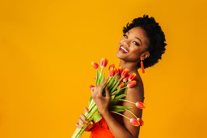 Smiling Black woman holding bouquet of tulips