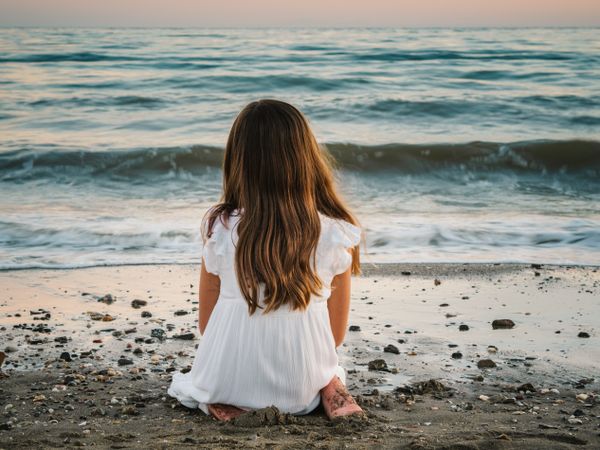 back view girl sitting on beach in daylight