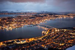 Majestic view of night city against snowy mountains in overcast weather