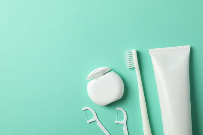 Tools for dental care on mint background, top view