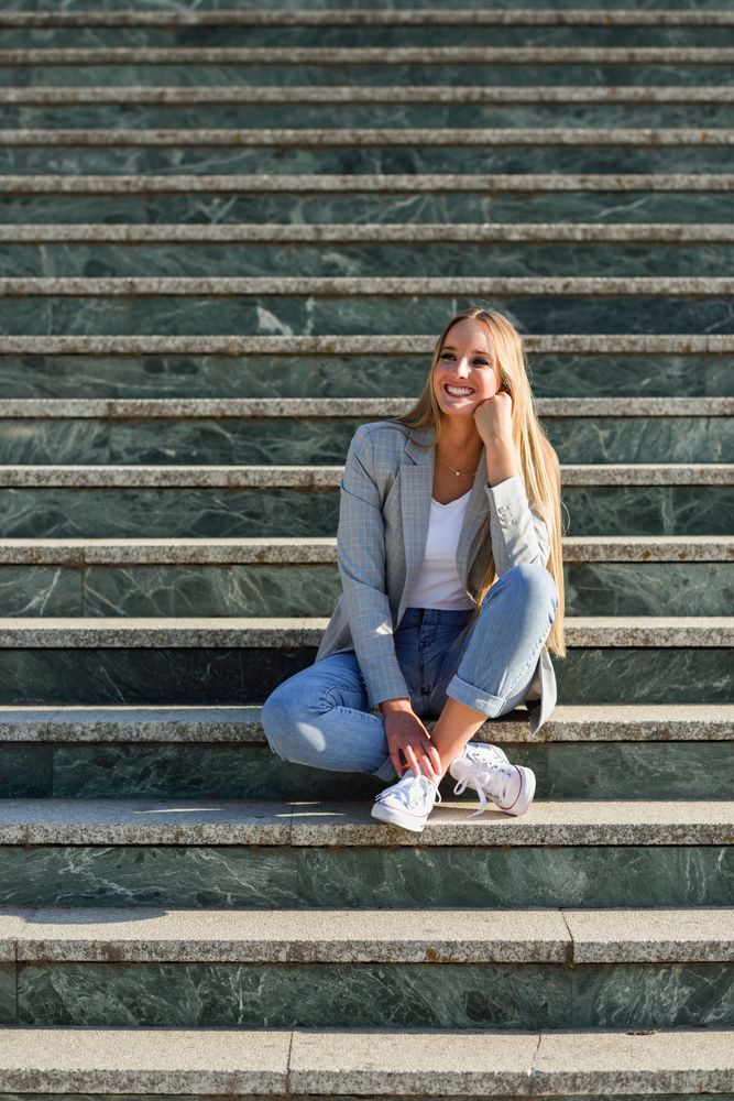 Smiling woman sitting on steps in contemplation