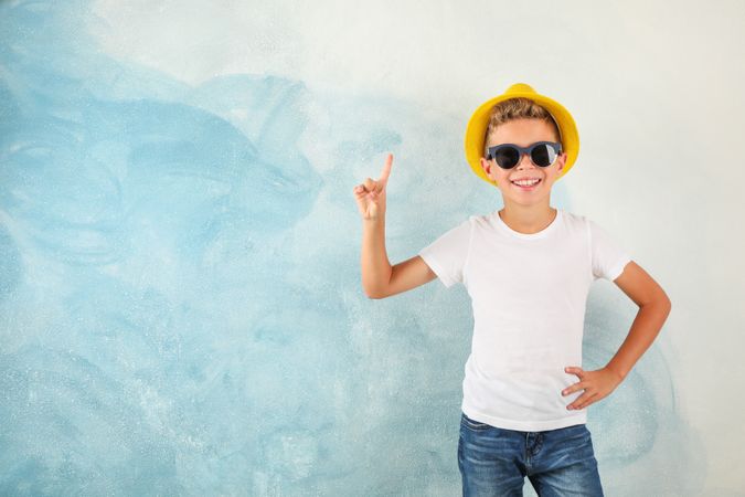 Boy with sunglasses and hat against color background, space for text