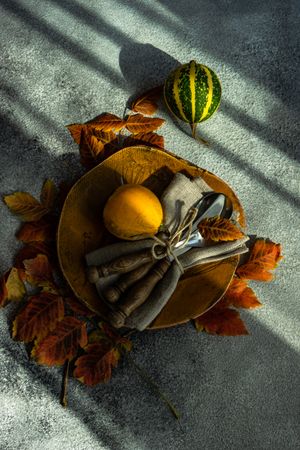 Fall table setting with orange leaves and squash on stone background with shadow