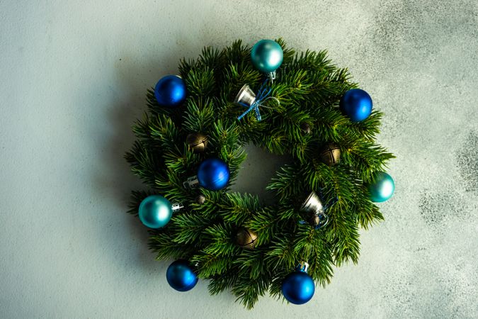 Christmas wreath with brass bells and blue baubles on marble counter
