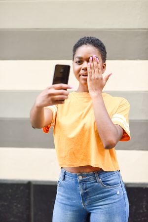 Female taking funny photo of herself in front of striped wall