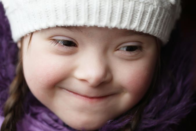 Closeup portrait of young girl with Down syndrome in a winter hat