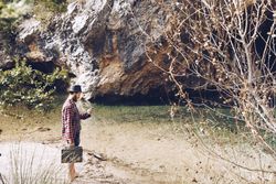 Man with case and smartphone on lake shore