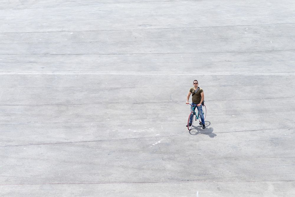 Male standing on bike on cement with space for text