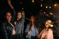 Multi-ethnic group of female friends dancing outdoors