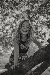 Smiling girl climbing tree in sunny day