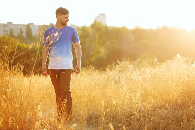 Man standing in grassy field at golden hour