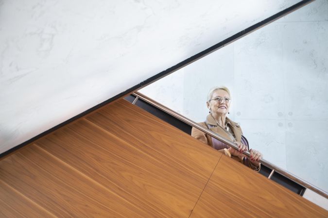 Mature woman in glasses looking down from stairs
