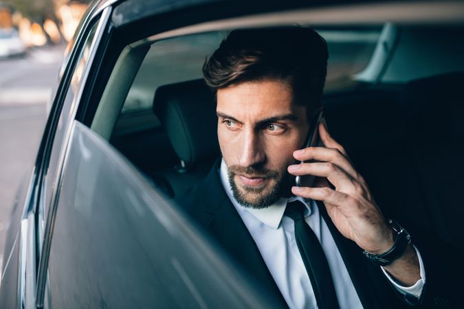 Male business executive traveling by a car and making phone call