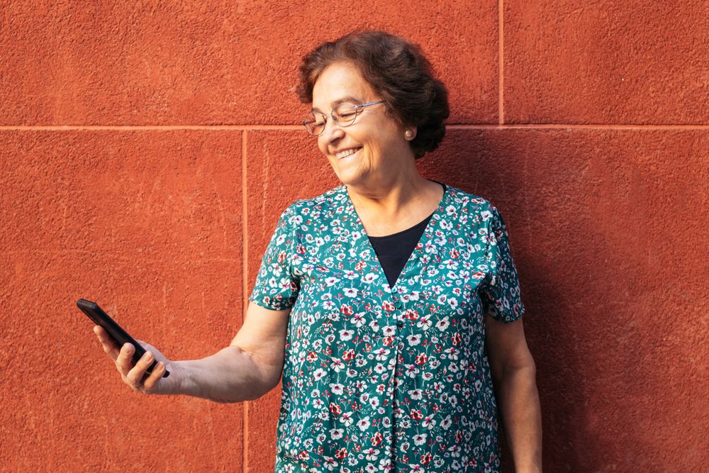 Smiling older woman using smartphone outdoors