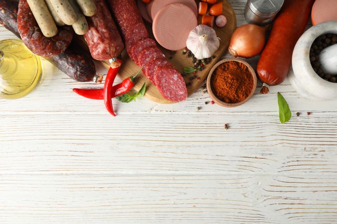 Selection of cured meats with peppers and spices on wooden background, copy space