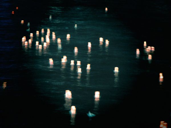 Lit paper lanterns floating on water at night