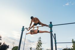 couple training together in a calisthenics park, doing back lever and straddle planche.
