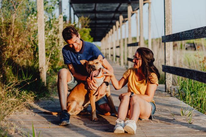 Happy adult couple having fun with dog at countryside