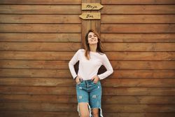 Woman leaning on wooden wall with two signs
