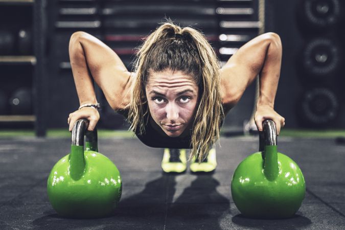 Muscular woman on hands in dumbbells in modern gym on blurred background