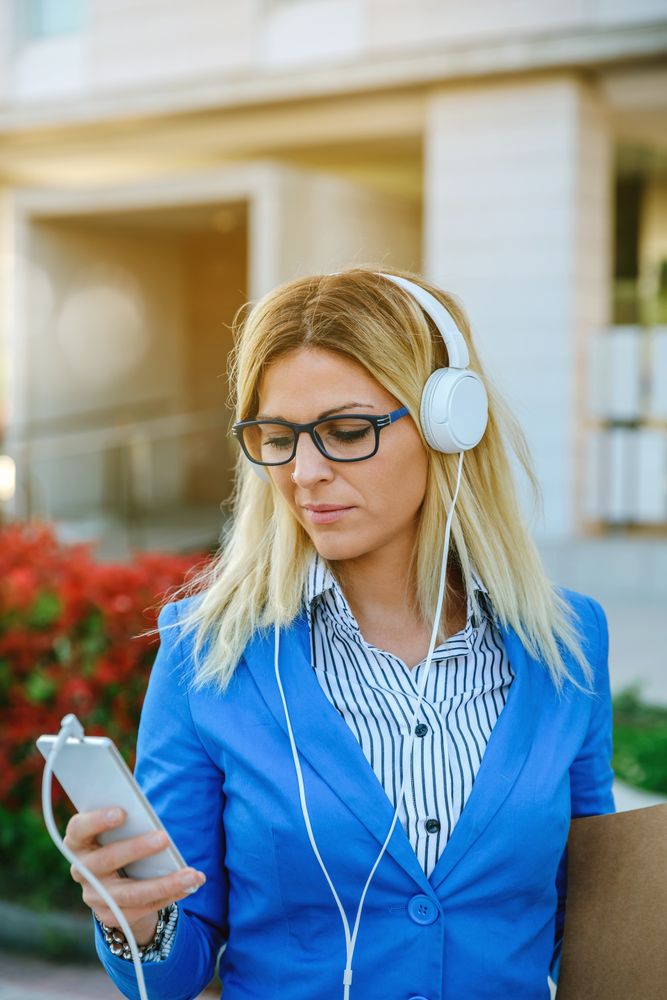 Businesswoman with headphones looking mobile