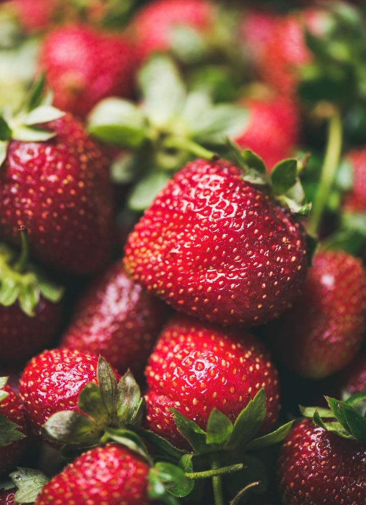 Freshly washed batch of strawberries, close up of one, vertical composition