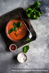 Tomato soup served with oil garnish and herbs, peppers and salt 5ng6pM