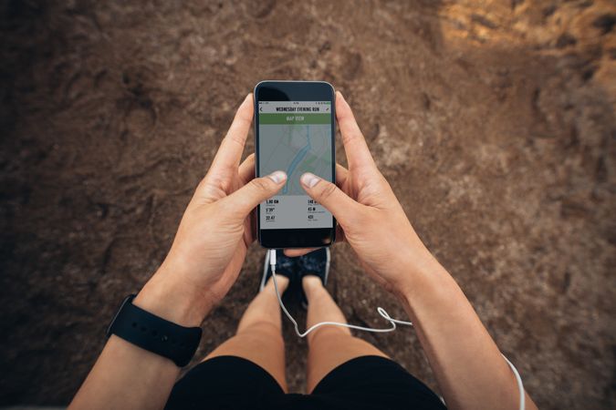 POV shot of woman runner using a fitness app on her cellphone