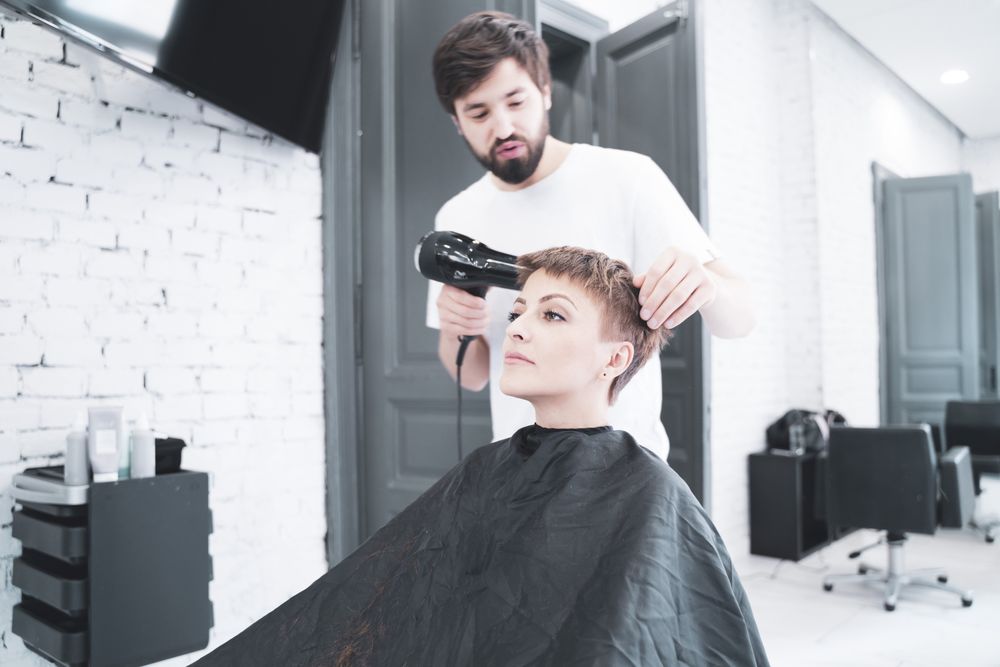 Hairdresser drying hair to woman
