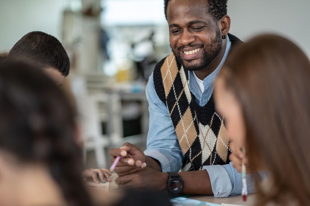 Smiling male teacher with students in classroom